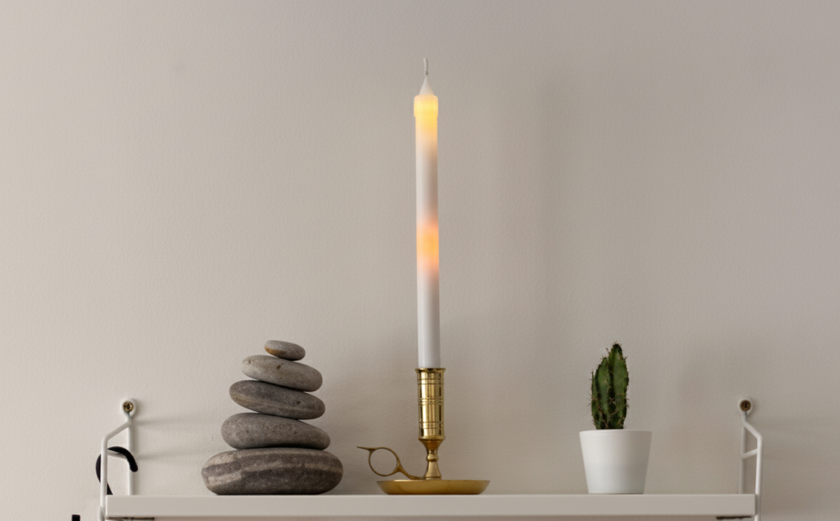 Photograph: Cand-EL, a lit candle-shaped device, staged on a shelf at home